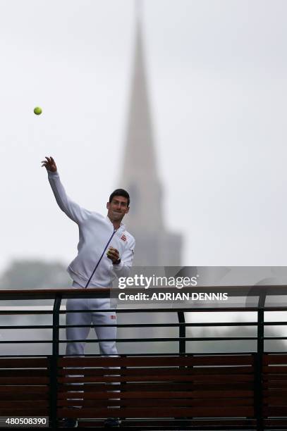 Serbia's Novak Djokovic stands on a balcony and throws tennis balls into the crowd after beating Switzerland's Roger Federer in the men's singles...