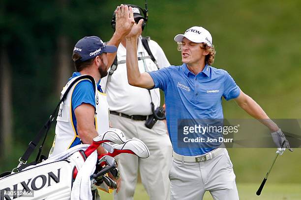 Will Wilcox celebrates with his caddie Kevin Ensor after hitting an eagle on the first hole during the final round of the John Deere Classic held at...
