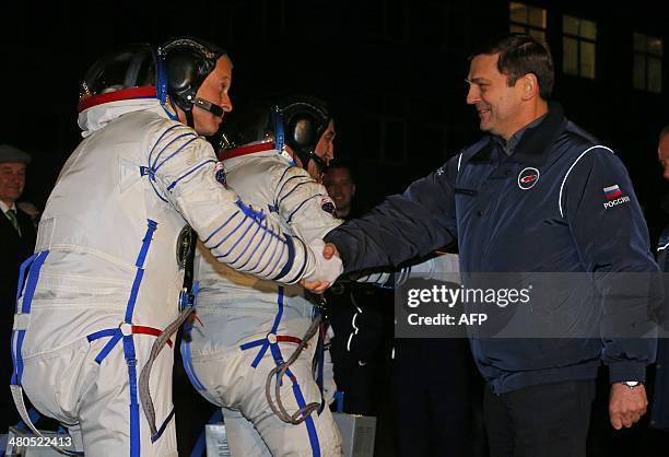 Russian Federal Space Agency Roscosmos head Oleg Ostapenko shake hands with US astronaut Steven, a crew member of a mission to the International...