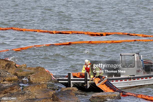 People with Garner Environmental Services work with oil booms that line the coast of East Beach on the Houston Ship Channel on March 25, 2014 in...