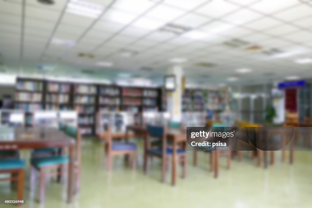 Blurry defocused image of book shelf, wooden desk and chair