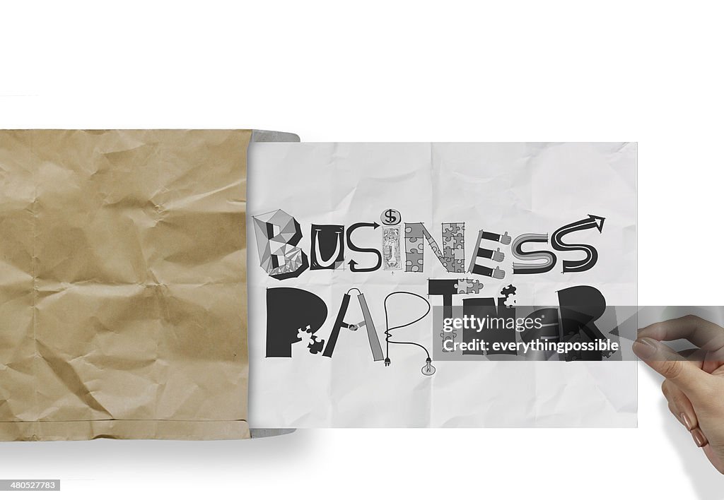 Hand pulling crumpled paper from envelope with design word BUSIN