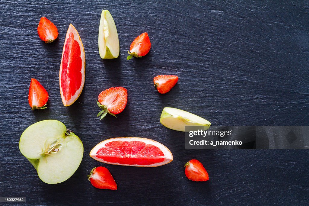 Apple, grapefruit and strawberry smoothie and ingredients, dark stone background