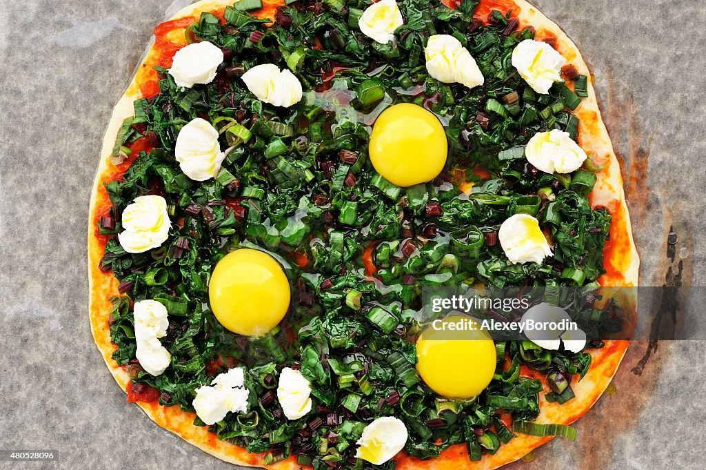 Raw round green pizza with chard, eggs and mozarella