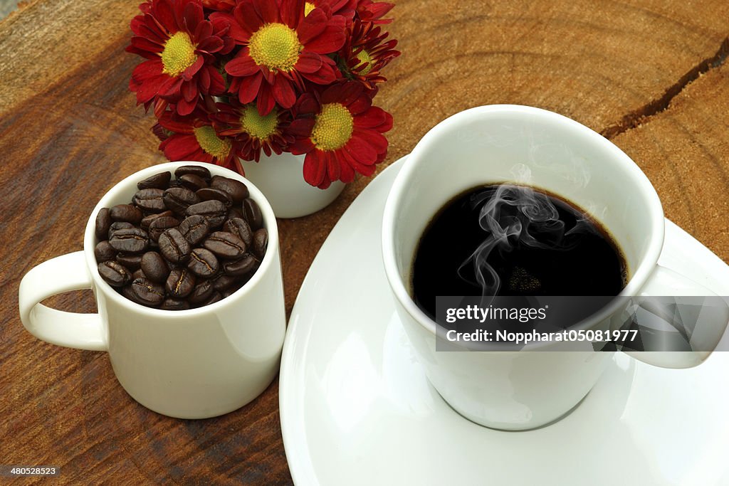 Copo de café e grãos em fundo de madeira.