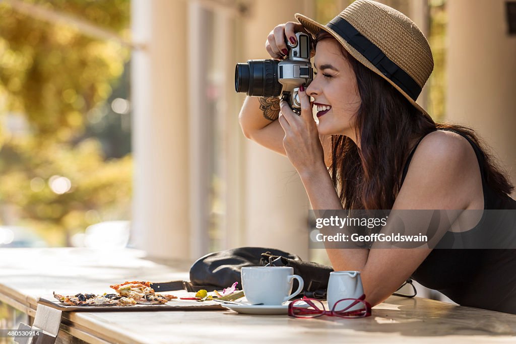 Young beautiful traveler happily taking photos with camera at ca