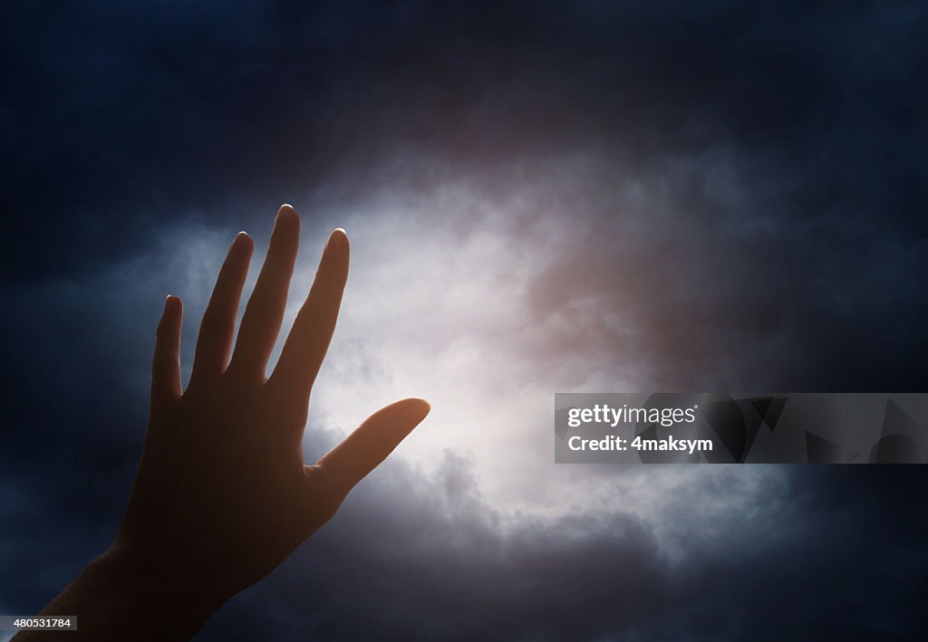 Hand reaching for the cloud in the sky