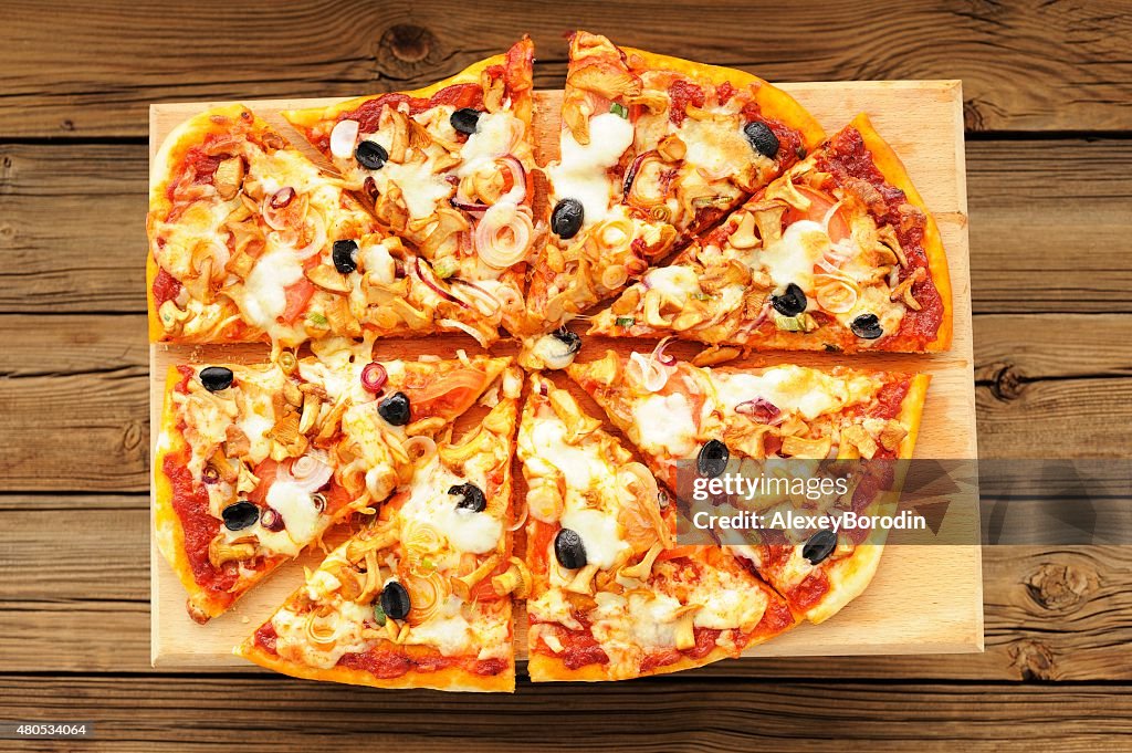 Al funghi pizza with olives cut in sectors on wooden