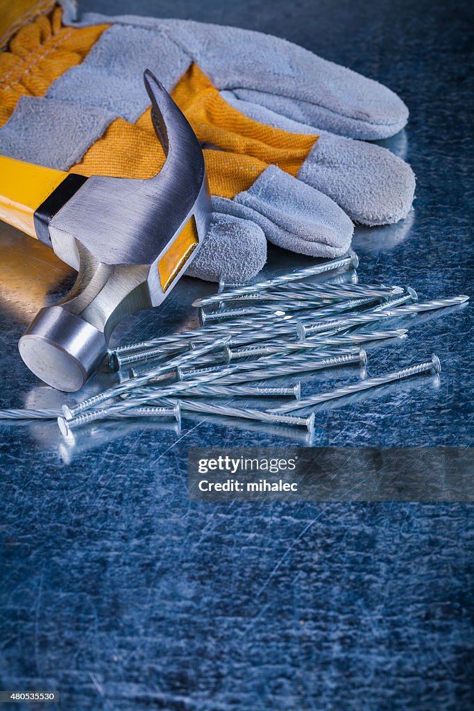 Safety glove collection of metal nails and claw hammer on