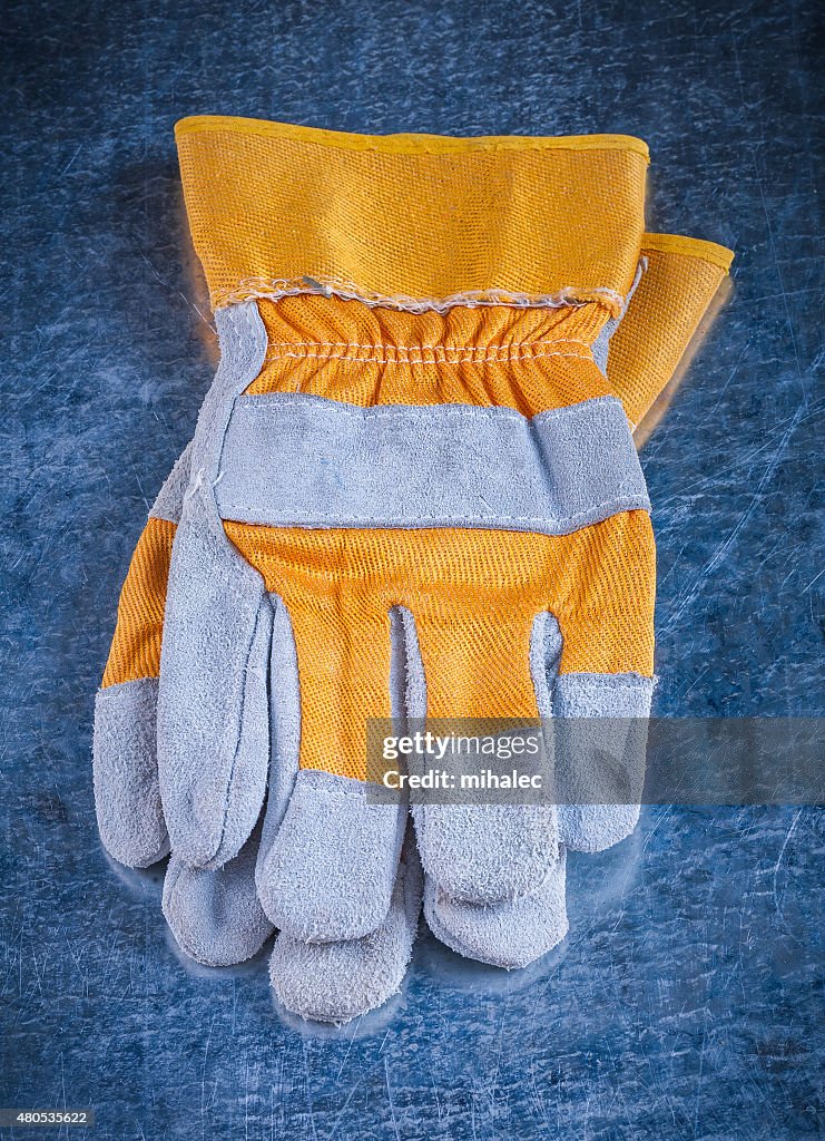 Protective working gloves on scratched vintage metallic backgrou