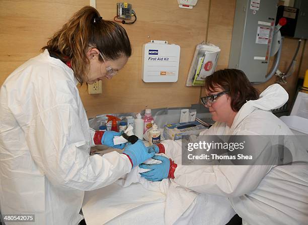 From left to right, Danene Birtell and Lisa Pittman with Wildlife Response clean and take vital signs of a Lesser Scaup duck on March 25, 2014 in...