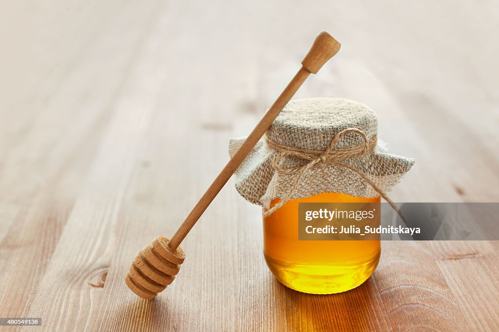 Honey in jar with twine, honey dipper, lemon and ginger