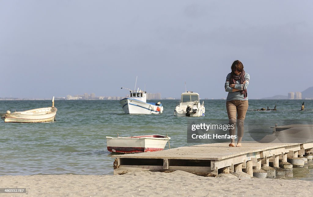 Attractive middle age woman thoughtfully walks along a beachside pier
