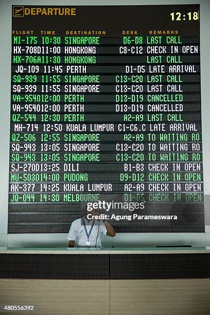 An airport officer is seen received a call infront of flight information board at Ngurah Rai international airport departure on July 13, 2015 in...