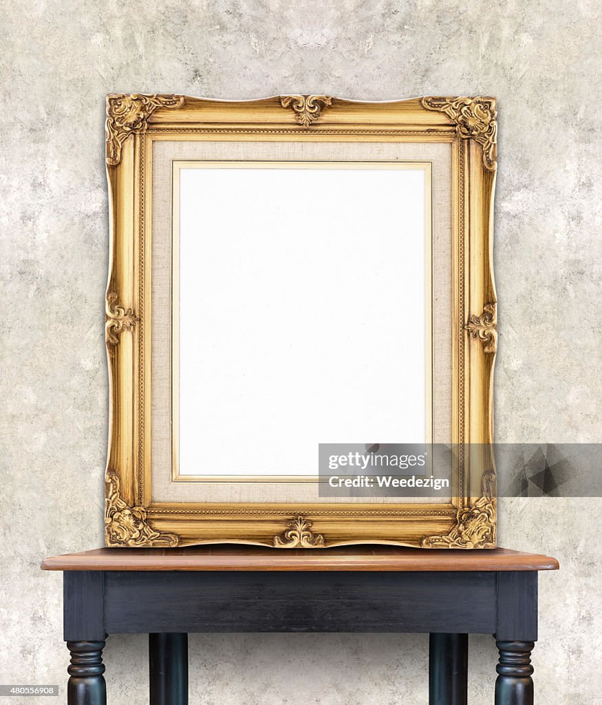 Blank vintage golden photo frame lean at light color concrete