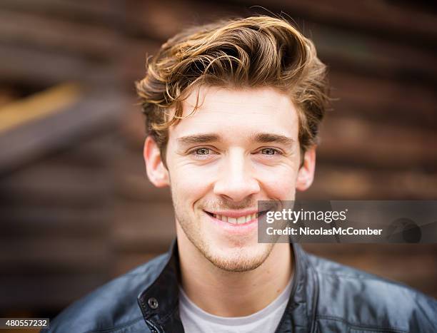 smiling handsome happy cheerful english male student wearing leather jacket - haardracht stockfoto's en -beelden