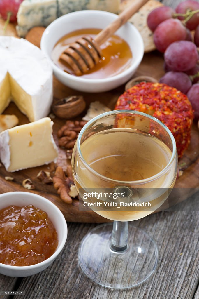 Glass of white wine, snacks on wooden table, top view