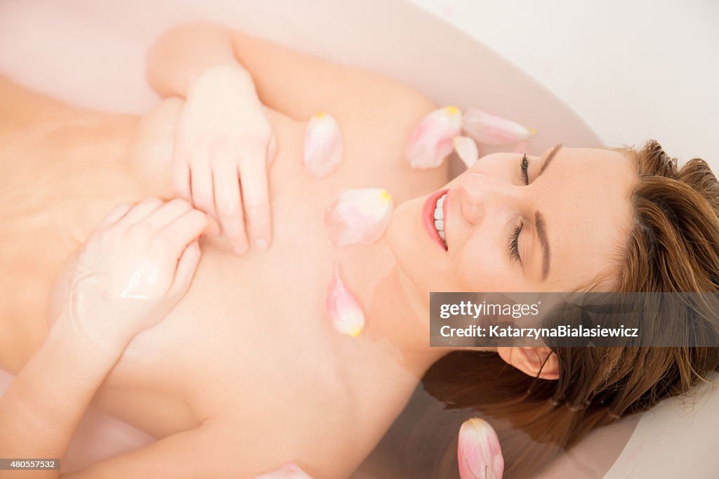 Woman takes a bath with rose petals