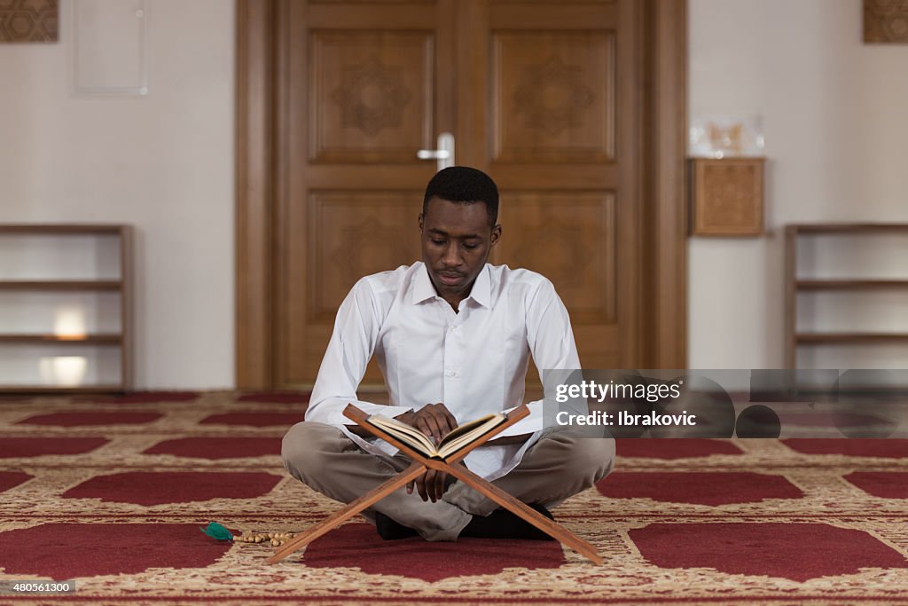 Young African Muslim Guy Reading The Koran