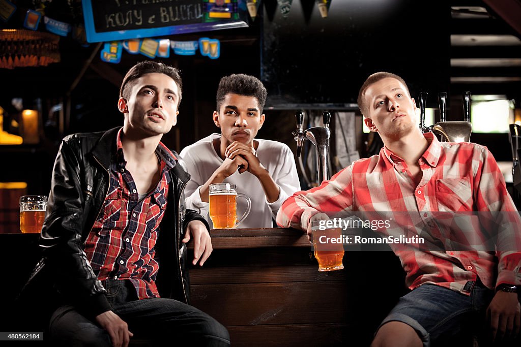 Watching TV in bar. men drinking beer sitting  bar