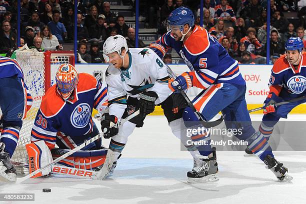 Mark Fraser of the Edmonton Oilers battles for the puck against Joe Pavelski of the San Jose Sharks on March 25, 2014 at Rexall Place in Edmonton,...