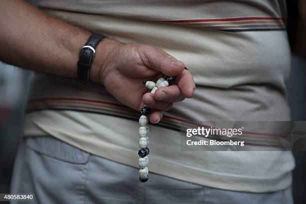 Pedestrian holds worry beads as he stops to read newspaper front pages outside a magazine kiosk in Athens, Greece, on Monday, July 13, 2015. Greece...
