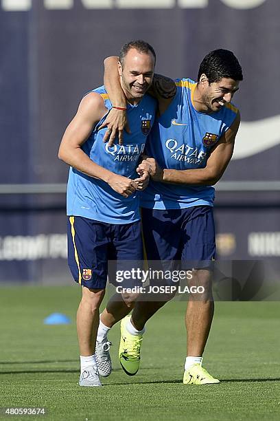 Barcelona's midfielder Andres Iniesta and Barcelona's Uruguayan forward Luis Suarez smile as they take part in the season's first training session at...