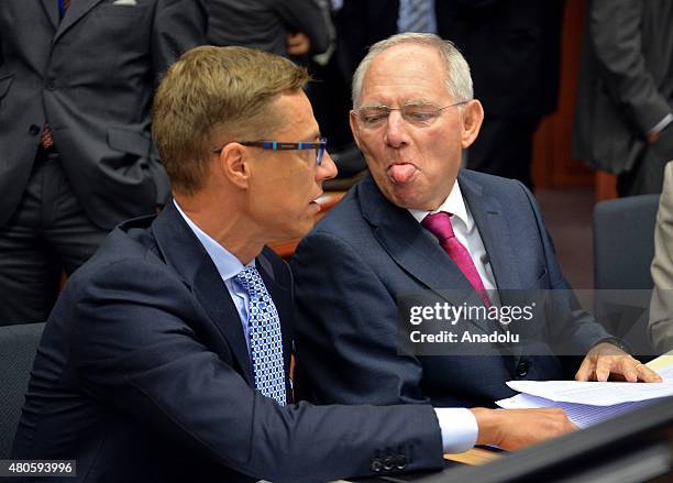 German Finance Minister Wolfgang Schauble sticks his tongue out at Finnish Finance Minister Alexander Stubb at the start of the Eurogroup finance...