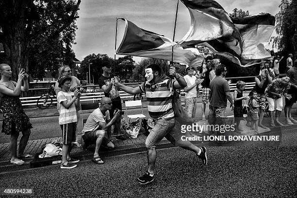 Supporter cheers running along the road during the 166 km second stage of the 102nd edition of the Tour de France cycling race on July 5 between...