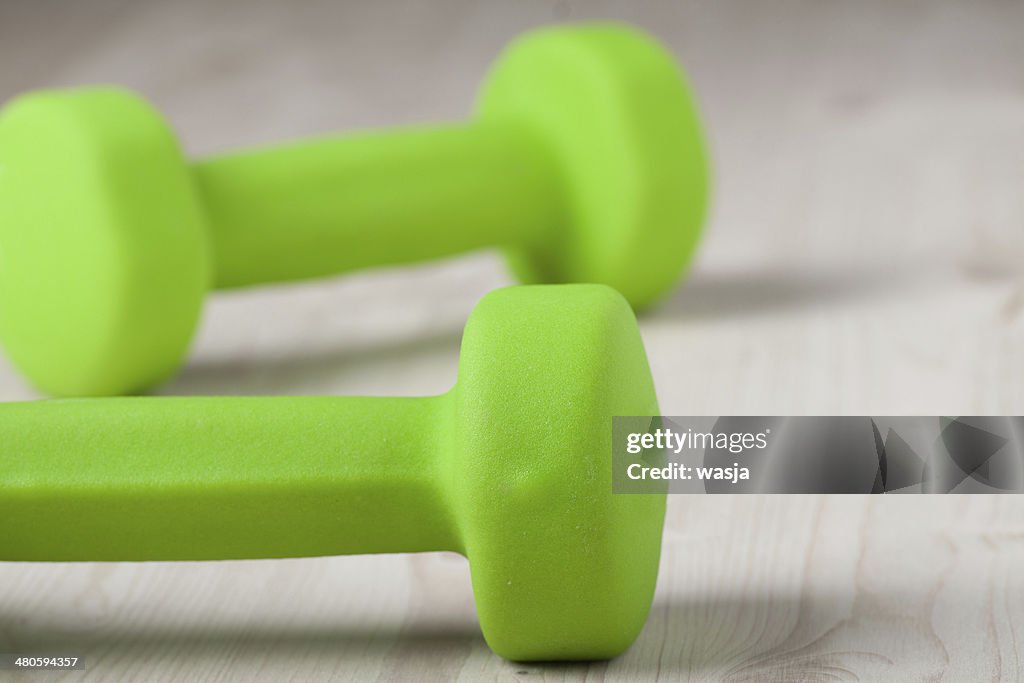 Pequeño, verde Mancuernas sobre la superficie de madera