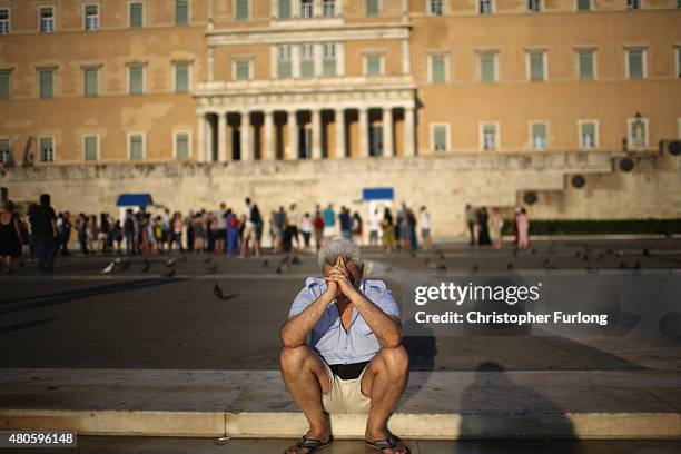 Man sits alone with his thoughts as protesters gather outside the Greek parliament to demonstrate against austerity after an agreement for a third...