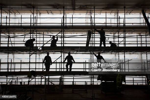 Employees stand on scaffolding as they work on the Royal Navy's new Queen Elizabeth class aircraft carrier, manufactured by the Aircraft Carrier...