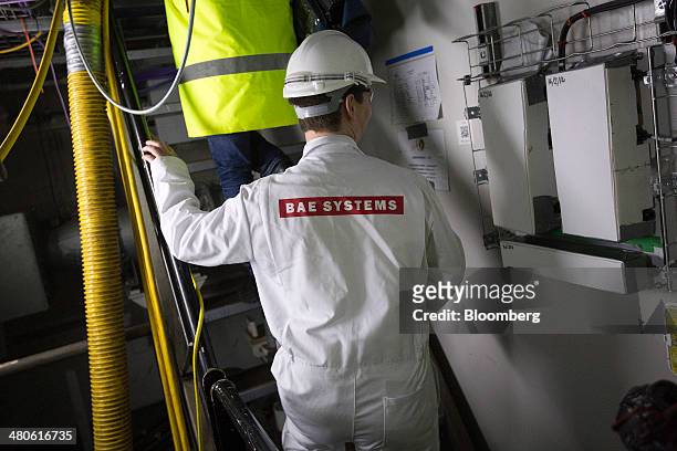 Worker wearing BAE Systems overalls climbs stairs between decks onboard the Royal Navy's new Queen Elizabeth class aircraft carrier, manufactured by...