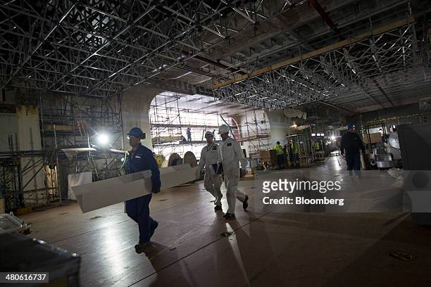 Workers walk along an inside deck onboard the Royal Navy's new Queen Elizabeth class aircraft carrier, manufactured by the Aircraft Carrier Alliance,...