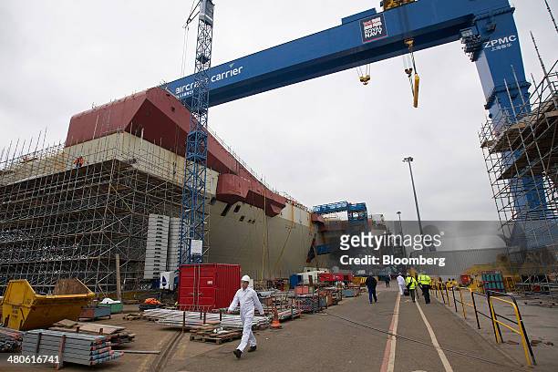 Workers walk along the dockside near the Royal Navy's new Queen Elizabeth class aircraft carrier, manufactured by the Aircraft Carrier Alliance, a...