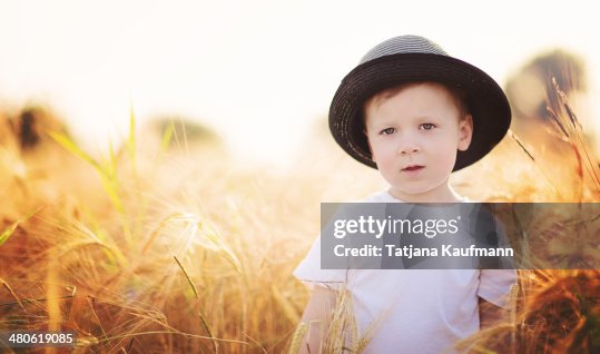 Little Boy with Hat standing in Field of Rye Crops Little Boy with Hat standing in Field of Rye Crops
