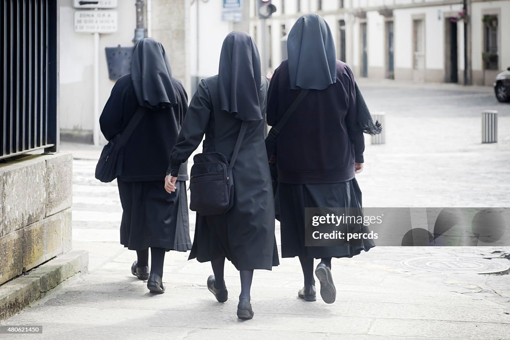 Rear view of three nuns walking in the street.