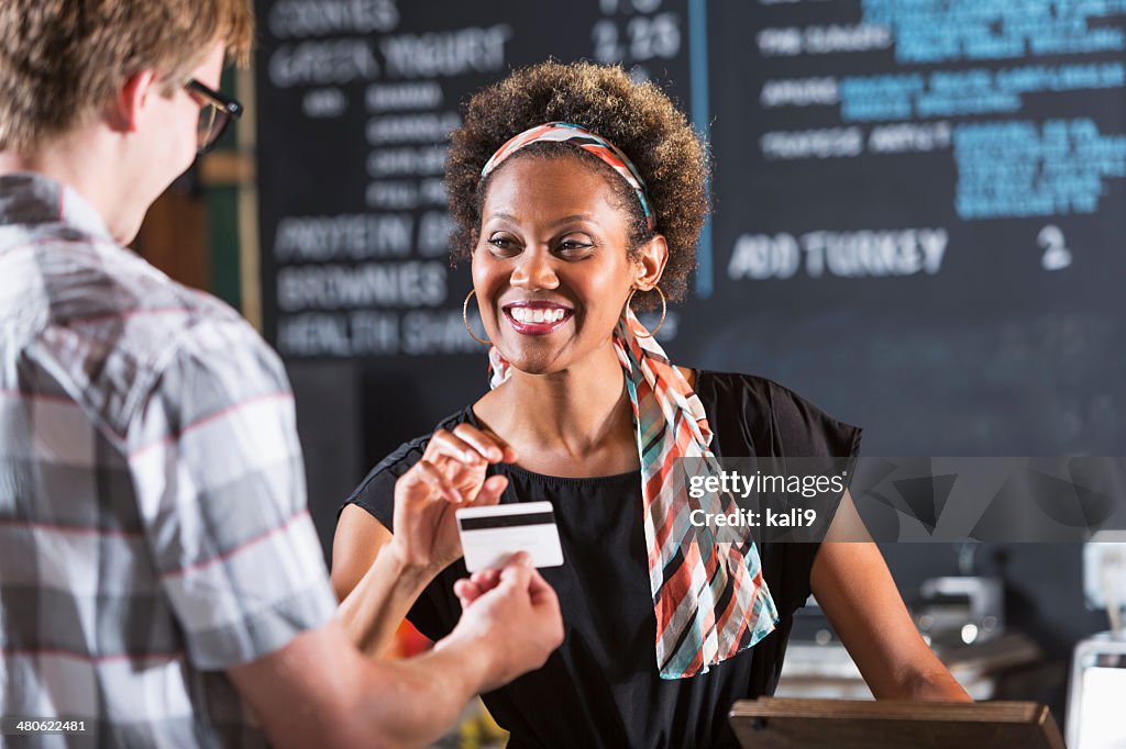 Woman working in restaurant taking payment from customer