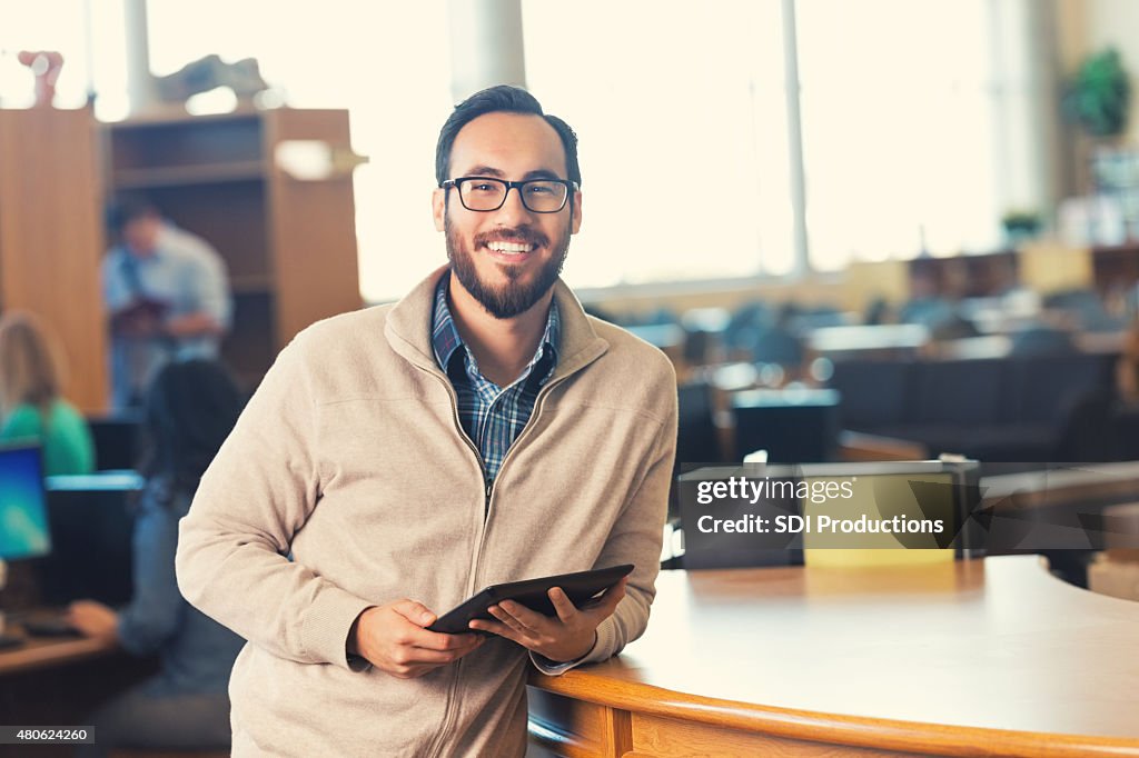 Trendy adulto ESTUDANTE UNIVERSITÁRIO em uma biblioteca com tablet digital