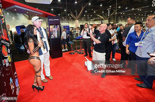 An attendee poses with a promotional model at the Square electronic cigarette booth at the 29th annual Nightclub & Bar Convention and Trade Show at...