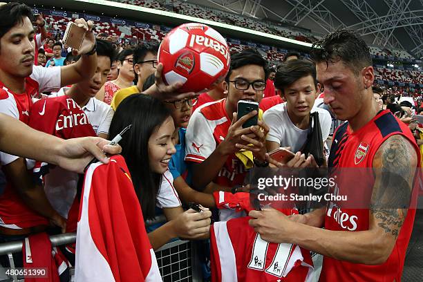 Mesut Ozil of Arsenal signs autographs for fans during the Arsenal FC open training ahead of the match between Arsenal and Singapore during the 2015...