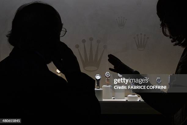 Visitors are seen in silhouette at the stand of Swiss watchmaker Rolex during the media day of 42nd edition of Baselworld watch fair on March 26,...