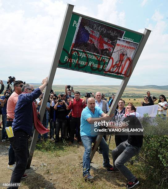 Protesters remove a border sign erected by Russian and Ossetian troops along Georgia's de-facto border with its breakaway region of South Ossetia in...