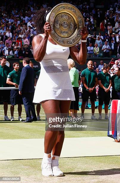 Serena Williams of United States hides behind the trophy after winning the Final of the Ladies Singles against Garbine Muguruza of Spain during the...