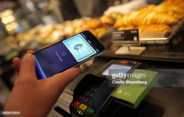 Customer uses an Apple Inc. IPhone to pay via the Apple Pay system, from their American Express Co., account, at the check-out till inside a Pret A...