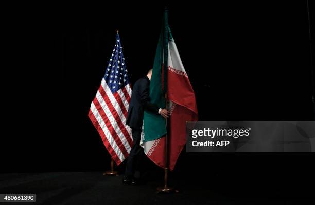 Staff removes the Iranian flag from the stage after a group picture with foreign ministers and representatives of Unites States, Iran, China, Russia,...