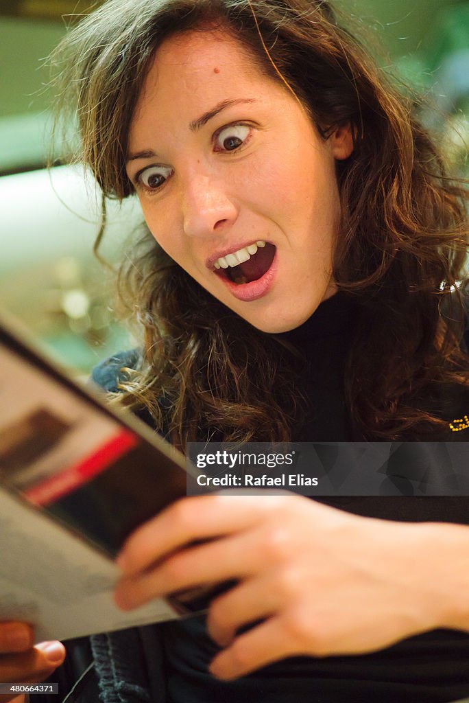Surprised woman reading magazine
