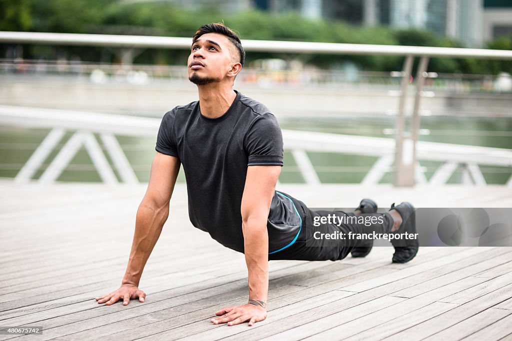 Uomo asiatico stretching su Singapore marina bay