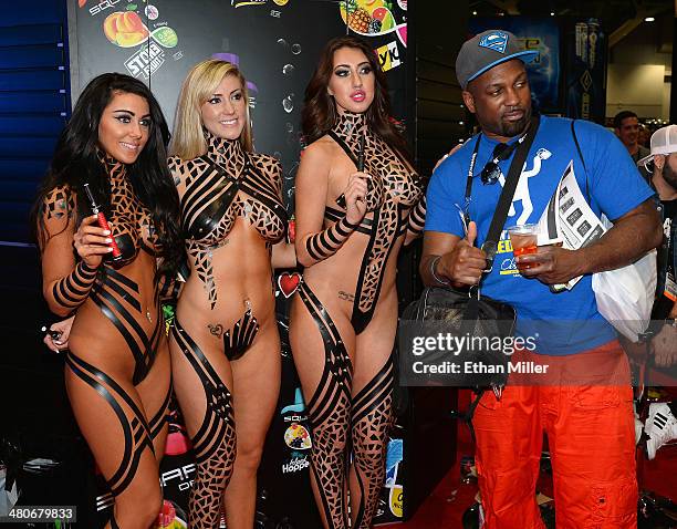 An attendee poses with promotional models at the Square electronic cigarette booth at the 29th annual Nightclub & Bar Convention and Trade Show at...