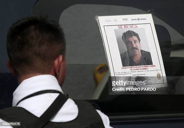 Federal Police officer stands next to a patrol car with a picture of fugitive drug lord Joaquin "El Chapo" Guzman's on its window, in Acapulco,...